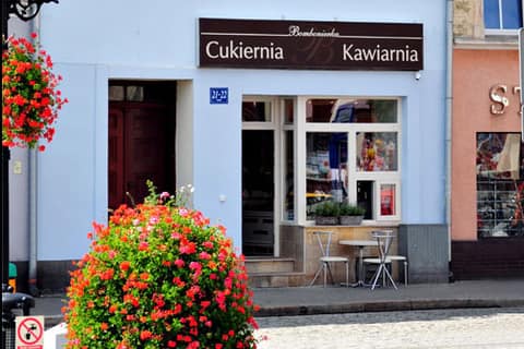 Błękitna fasada cukierni Bombonierka przy Rynku w Grodkowie z kwiatami przed wejściem