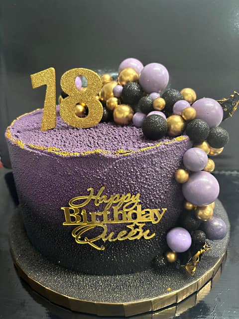 Fioletowy tort na osiemnaste urodziny ze złotymi kulami i napisem Happy Birthday